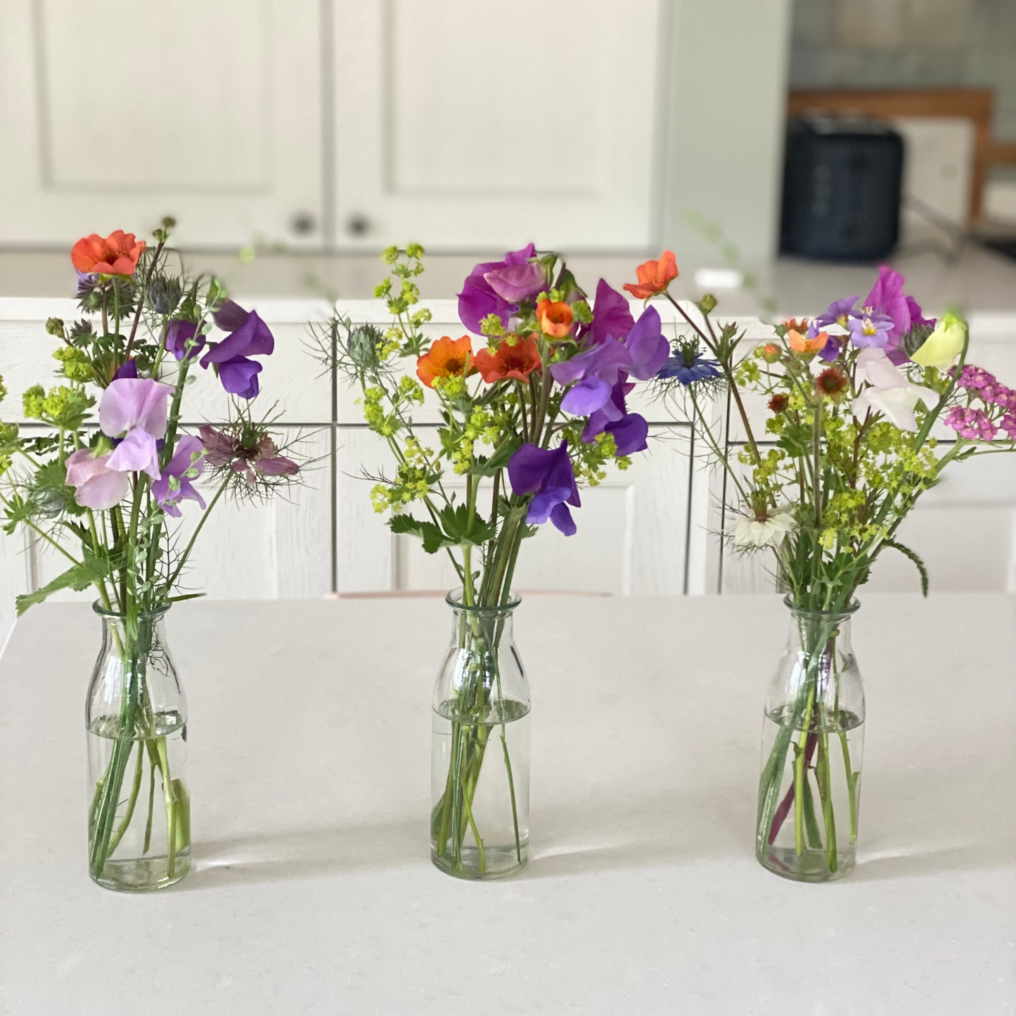 Gevulde tafelvaasjes met seizoensbloemen